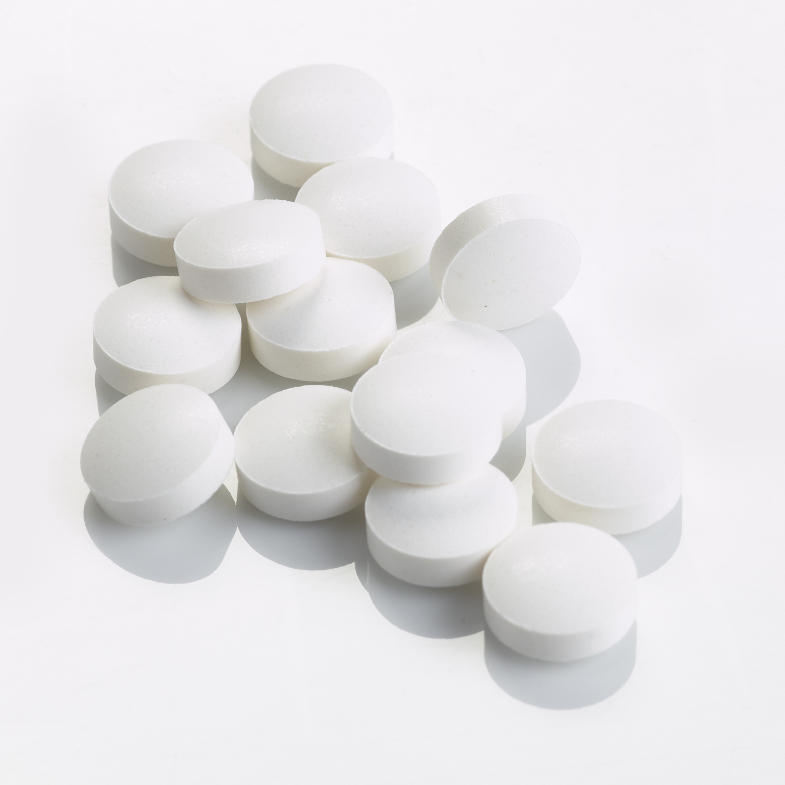 Pile of white coloured Vitamin B6 tablets on a flat surface.