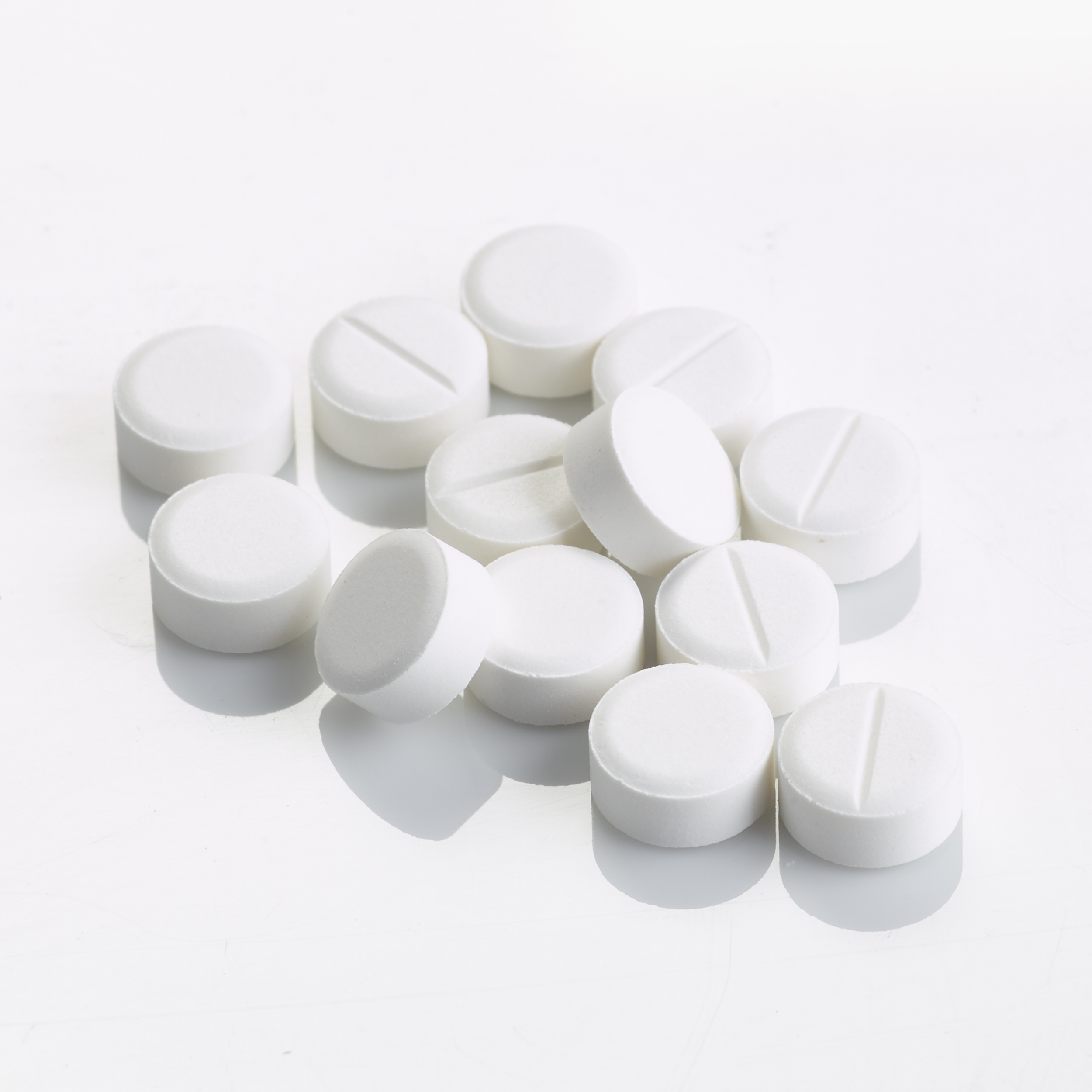 Pile of white coloured Vitamin D3 tablets on flat surface.